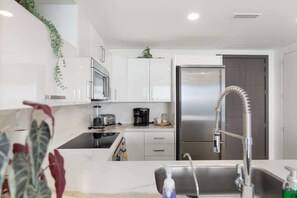A modern kitchen with white cabinets, stainless steel appliances, and a built-in oven.