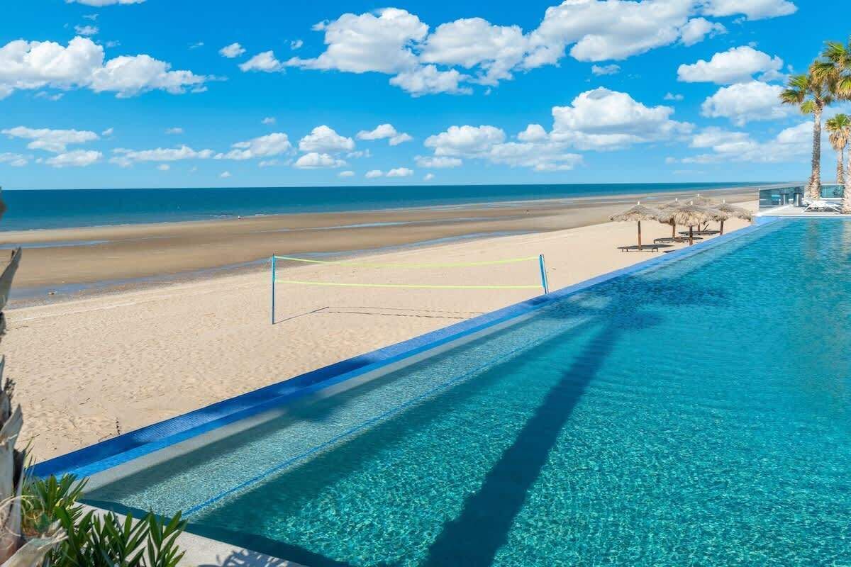 Ein klares, blaues Schwimmbecken mit Blick auf den Strand und den Ozean.