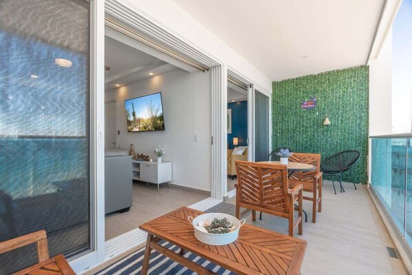 A modern living area with a dining set, a TV, and a green wall.