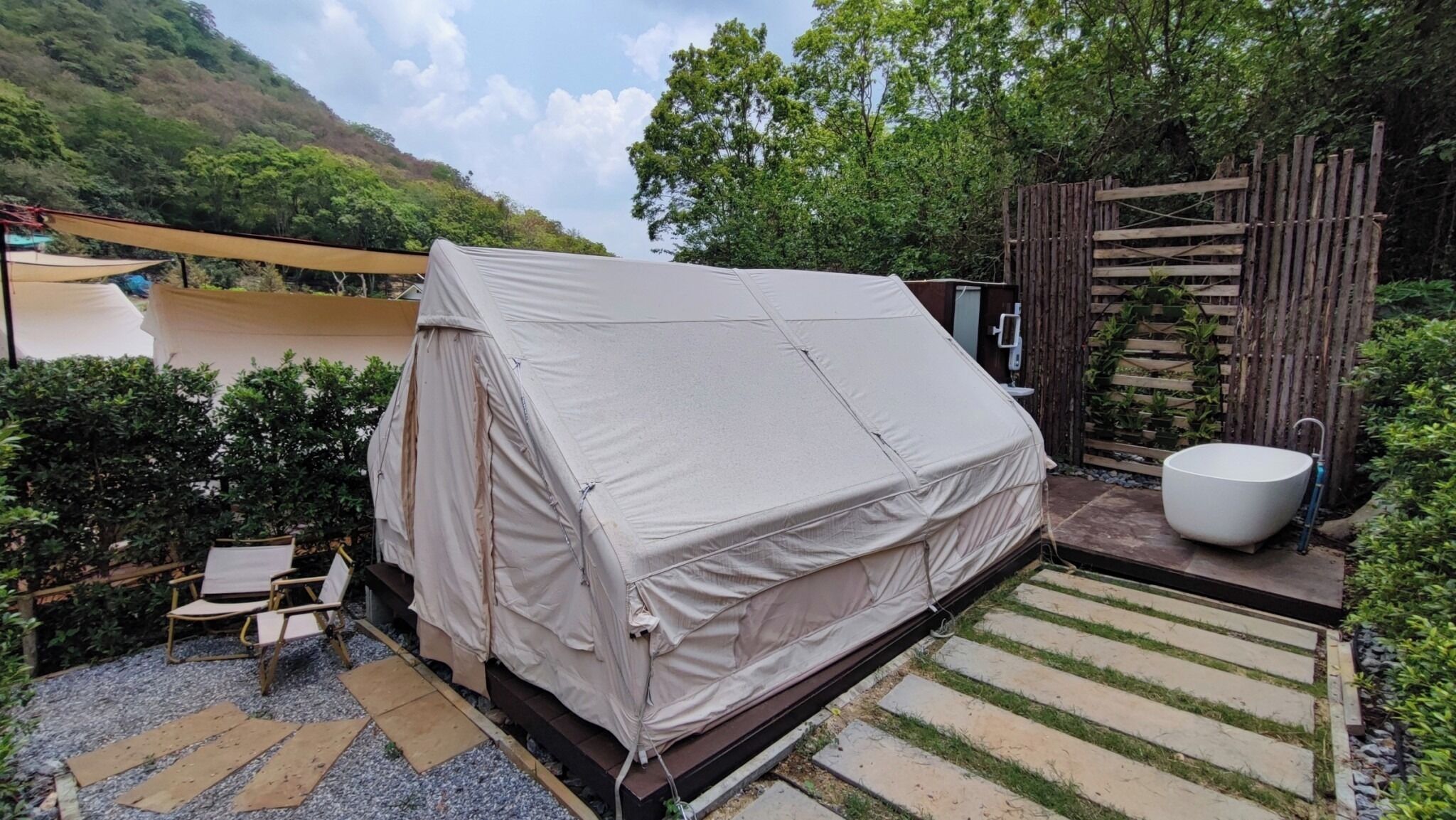 A covered outdoor seating area with a table and chairs, a large covered tent, and a bathtub.