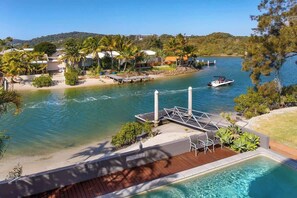 A resort with a swimming pool, a dock, and a boat on the water.