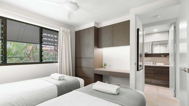 A hotel room with two beds, a bathroom, and a view of the outdoors.