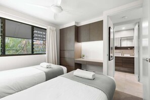 A hotel room with two beds, a bathroom, and a view of the outdoors.