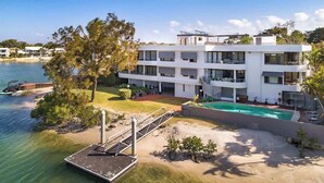 A modern multi-story building with a pool, located near a body of water.