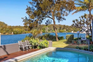 Piscina com vista para um lago e árvores ao redor.