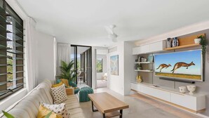 A modern living room with a sofa, coffee table, and a TV displaying kangaroos.