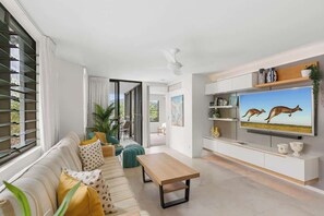A modern living room with a sofa, coffee table, and a TV displaying kangaroos.