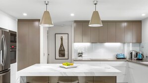 A modern kitchen with a central island, pendant lighting, and stainless steel appliances.