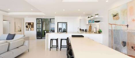 A modern kitchen with a central island, bar stools, and a dining area with a sofa.