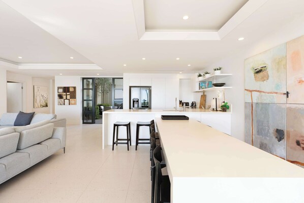 A modern kitchen with a central island, bar stools, and a dining area with a sofa.