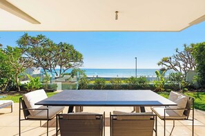 An outdoor patio with a table and chairs, overlooking a beach.
