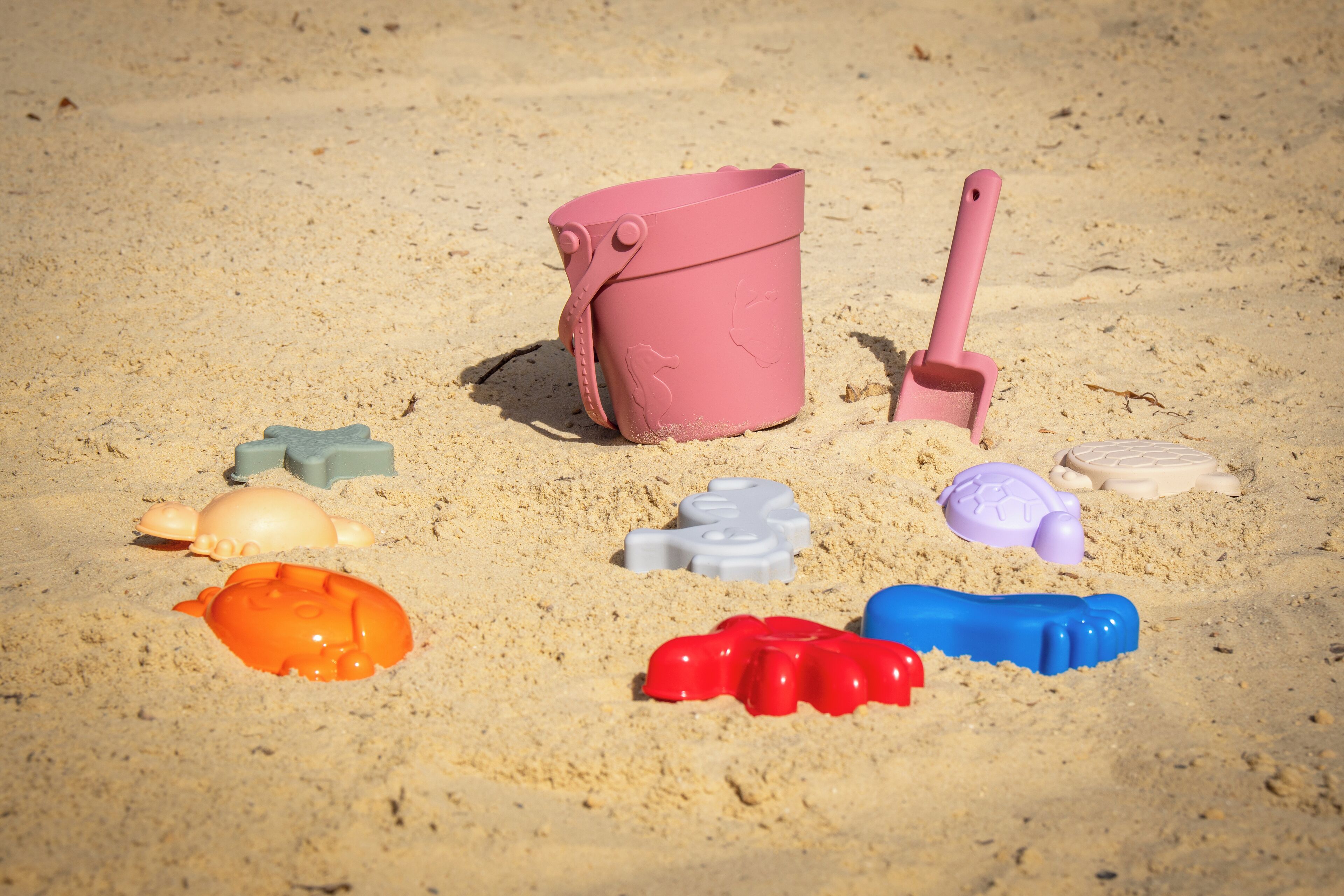 A collection of beach toys on sandy ground.