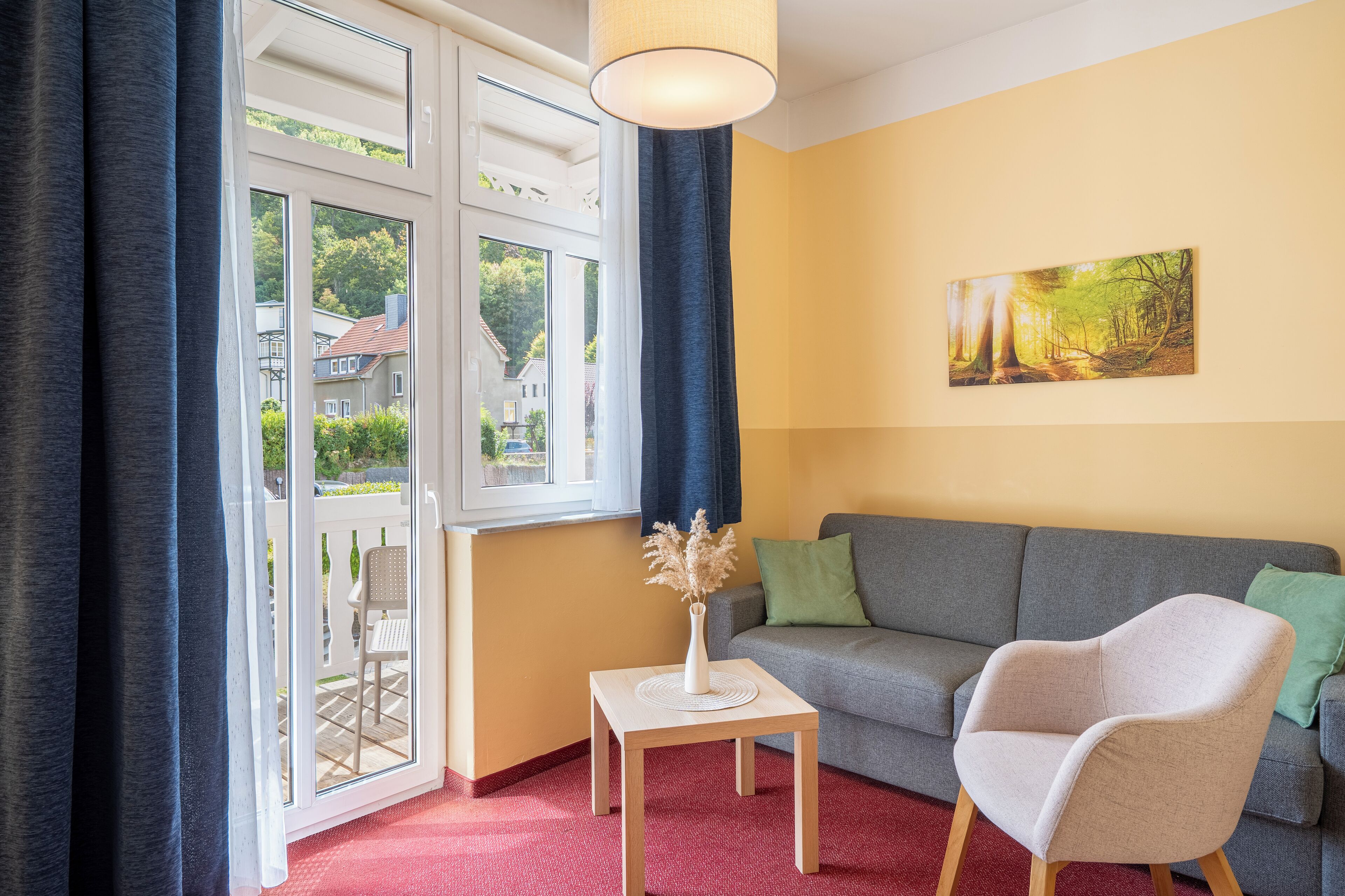 Un salon avec un canapé, un fauteuil, une table sur laquelle se trouve un vase, et un tableau accroché au mur.