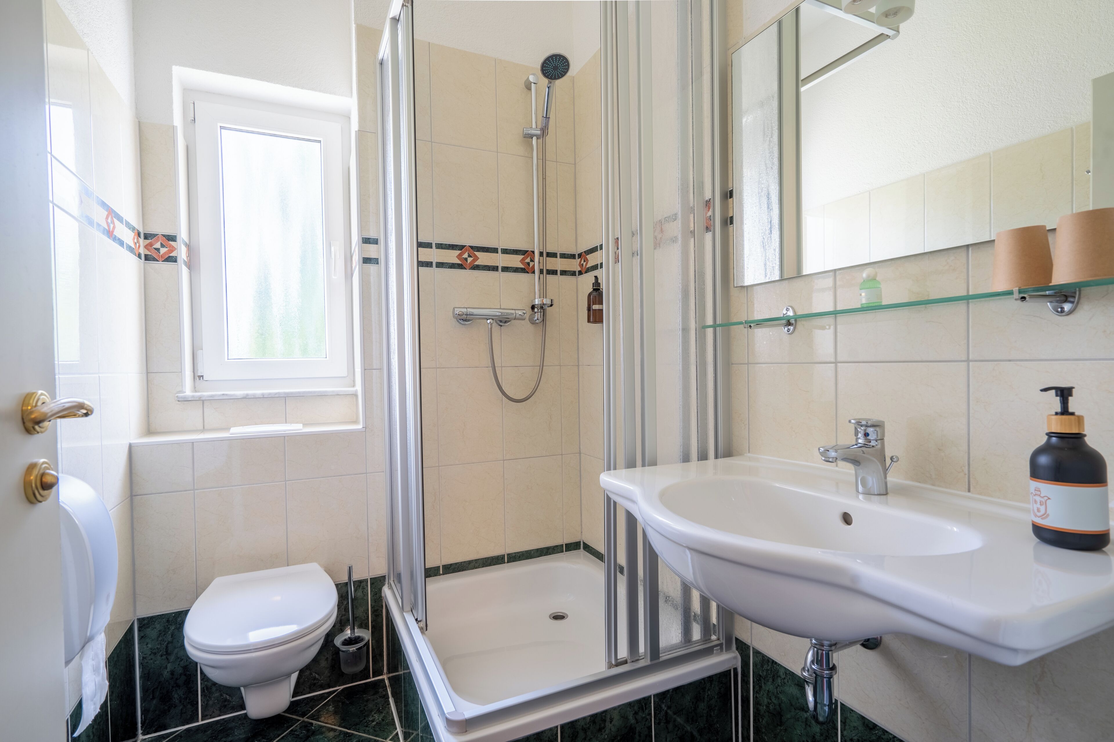 A bathroom with a shower, toilet, sink, and a window.