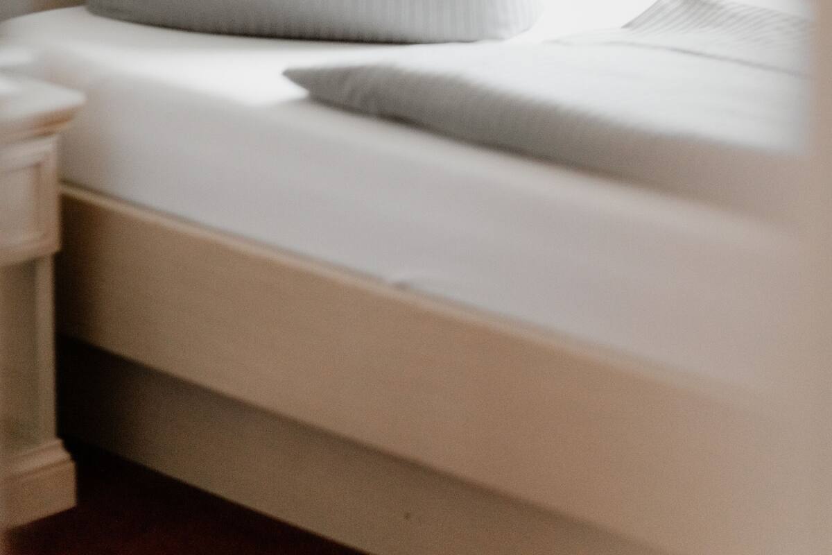 A bed with a headboard, two pillows, and a bedside table.