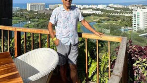 A man standing on a balcony with a view of a golf course, buildings, and a body of water. - Home in Flamingos Residencial. (Bucerías)