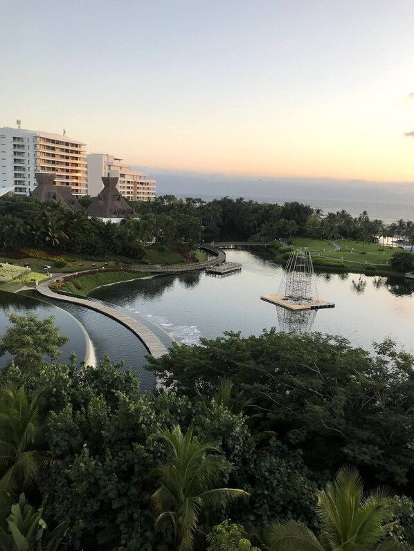 A resort with a water feature, palm trees, and a view of the ocean.