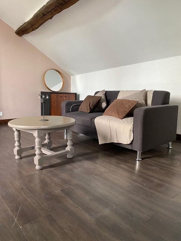 Relax in this stylish living room with a round table, grey sofa, and wooden cabinet.