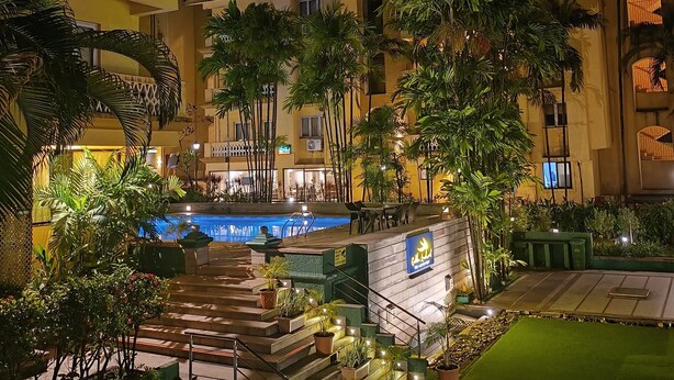 Ein Hotelinnenhof mit Pool, Sitzgelegenheiten im Freien und üppiger Bepflanzung.
