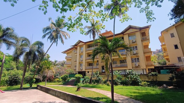 A multi-story hotel with balconies, surrounded by lush greenery and palm trees. - Golden Landmark Green Valley Beach Resort (Panaji)