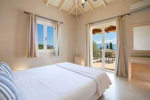 A bedroom with a large bed, a view of the outdoors, and a sliding glass door leading to a patio. - Villa Olivia in Perigiali (Lefkada)
