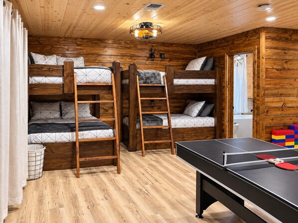 Ein Zimmer mit Stockbetten, einem Tischtennisplatten und Holzwänden.
