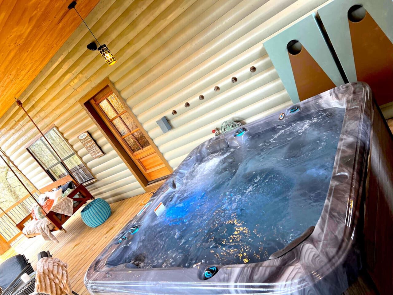 A hot tub in a log cabin-style room with wooden walls and a sloped ceiling.