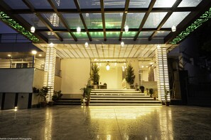 A hotel entrance with a glass canopy, steps leading up to the door, and potted plants. - Mountain Midst (Dehradun)