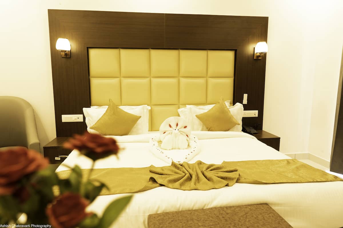 A hotel room with a large bed, two nightstands, a lamp, and a bouquet of roses.