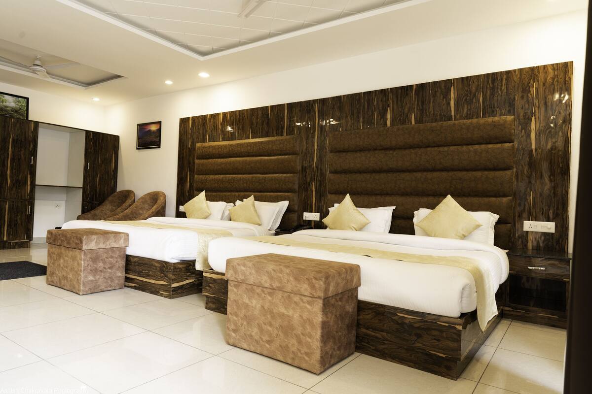 A modern hotel room with two beds, a large mirror, and a wooden accent wall.