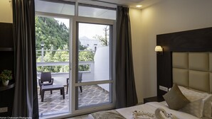 Habitació d'hotel amb una gran porta corredissa de vidre que dona a un balcó exterior. La habitació té un llit amb roba de llit blanca, un panell de capçal fosc i una tauleta de nit amb una làmpada.