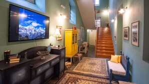 Ein geräumiger Wohnbereich mit großem Flachbildfernseher, einer Holztreppe und einer gemütlichen Sitzecke mit Sofa und Bank.