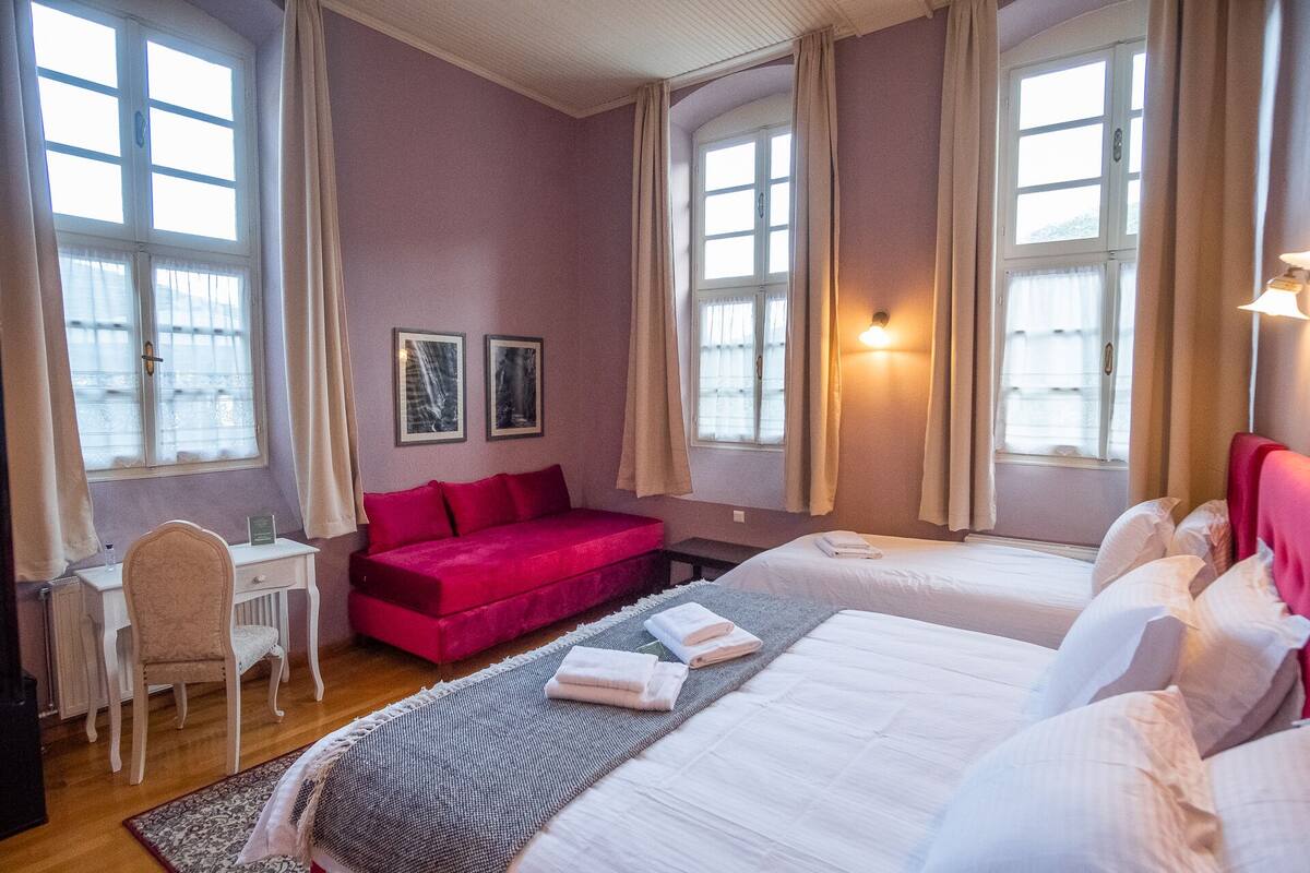 Une chambre d’hôtel avec deux lits, un bureau, une chaise et deux tableaux encadrés au mur.