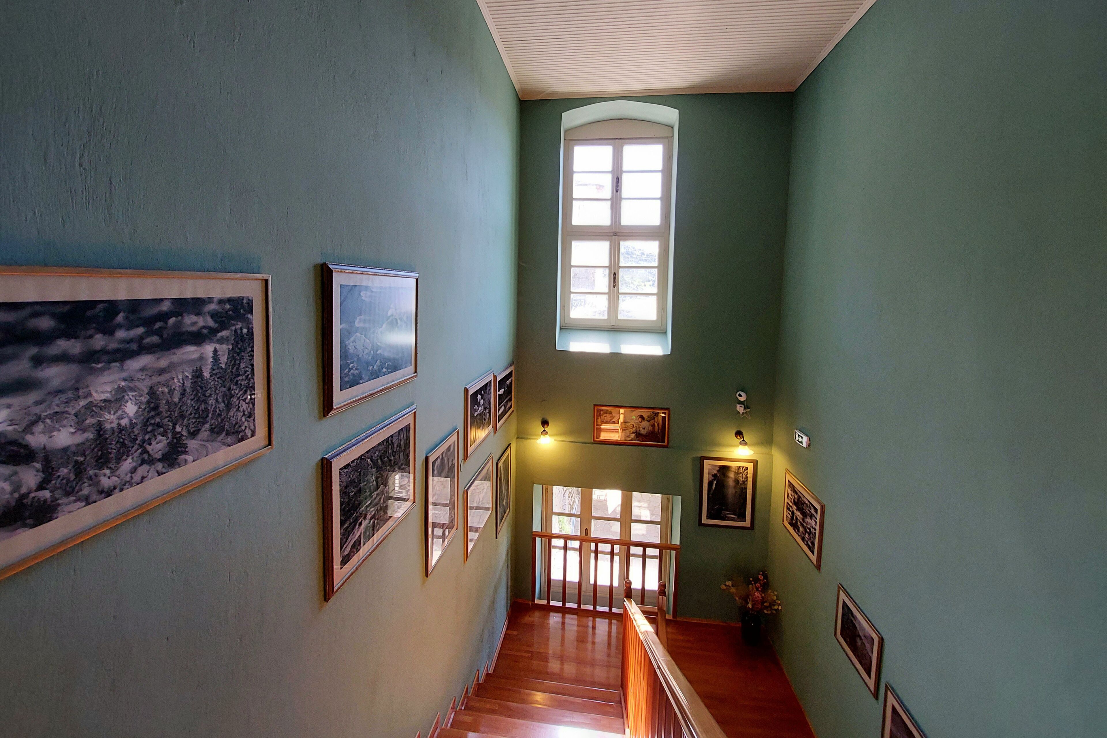 A staircase with wooden steps leading to a landing, flanked by walls adorned with framed pictures.