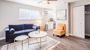 A living room with a blue sofa, an orange chair, a coffee table, and a ceiling fan. - Cozy, Central 1B Apt Close to UC Hospitals, DT (Norwood)
