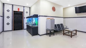 Un vestíbulo con una recepción, un acuario, un refrigerador, un banco y un televisor montado en la pared.