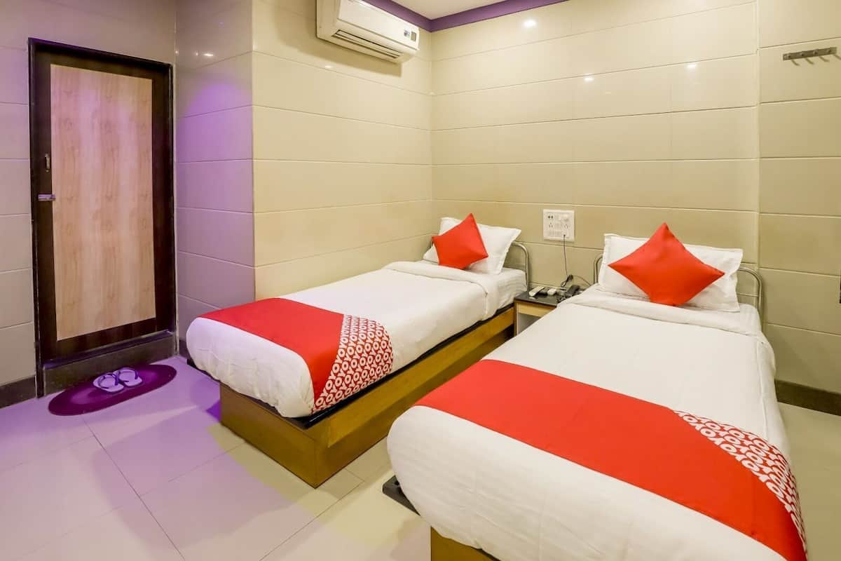 A hotel room with two beds, a wooden door, an air conditioning unit, and a purple mat.