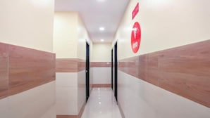 Un pasillo moderno con piso blanco brillante, paneles de madera en las paredes y una señal circular roja en la pared derecha.