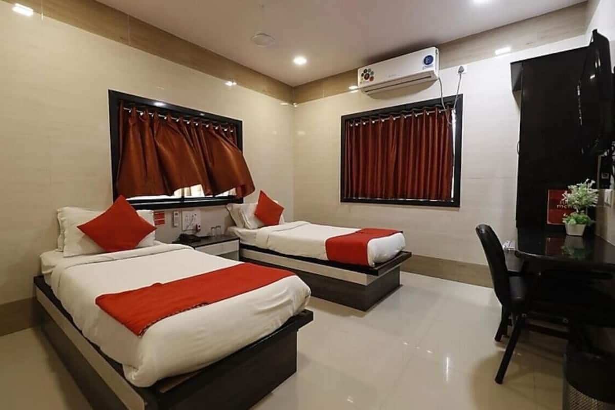 A hotel room with two beds, a desk, and a chair. There is an air conditioning unit on the wall.