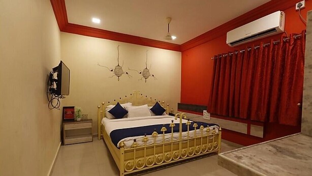 Un dormitorio con cama, mesita de noche, aire acondicionado y cortina roja.