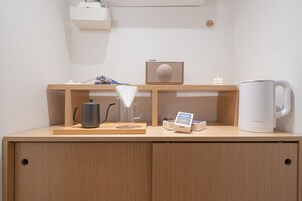 Un escritorio de madera con una tetera, una radio y una caja de pañuelos.