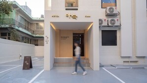 Ein Hotel Eingang mit modernem Design, inklusive Schild mit koreanischen Schriftzeichen und einem Slogan.