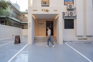 Entrada de hotel con diseño moderno, que presenta un letrero con caracteres coreanos y un eslogan.