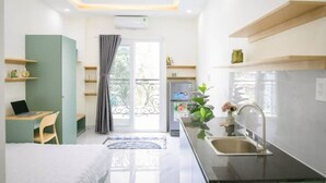 A modern kitchen with a built-in oven, a sink, and a small dining area with a table and chair. - 2/studio Neuf, Confortable et Coloré Avec Balcon (Ho Chi Minh City)