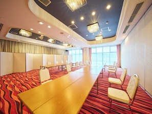 Une salle de conférence avec une longue table, des chaises et un tapis à motifs.