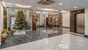 Een moderne lobby met een marmeren vloer, een kerstboom en een lift.