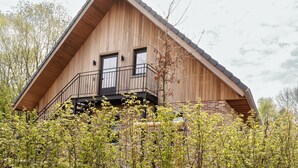 Una cabaña de madera con balcón y cimientos de ladrillo.