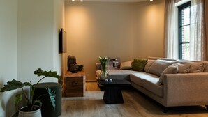 Una sala de estar moderna con un sofá color beige, una mesa de centro negra y una planta en maceta.
