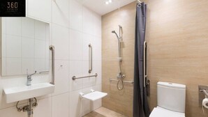 A modern bathroom with a white sink, mirror, and toilet. It includes a shower with a handheld showerhead and a grab bar. - Stylish 1BR Meridian in central St Julians (San Ġiljan)