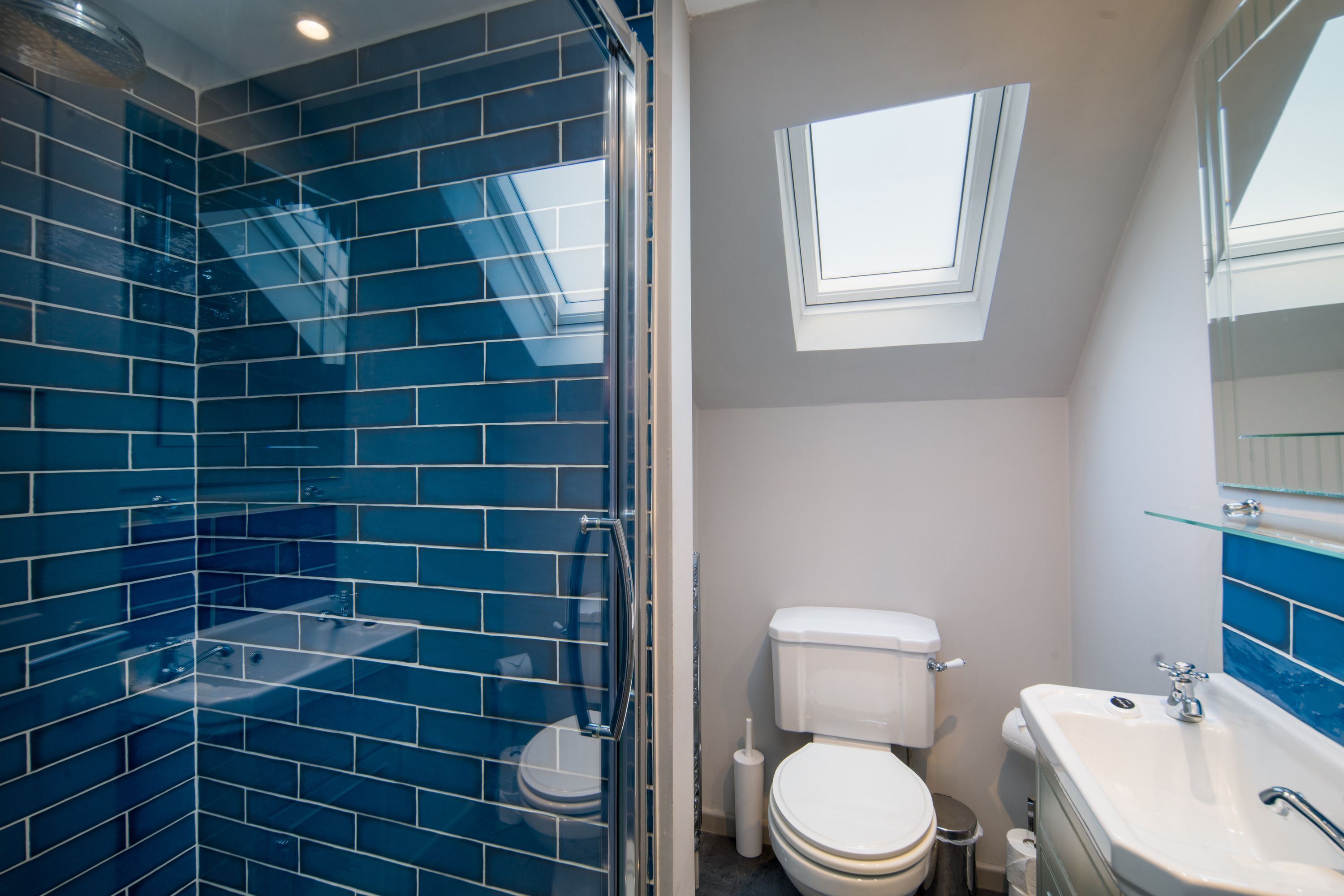 A bathroom with a glass shower enclosure, a white toilet, and a sink.